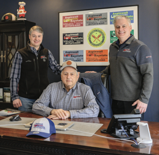 Aspinwall Plumbing & Heating founder Lou Mazzini sits at a desk with his sons, Michael and Christopher, standing behind him. | Aspinwall Plumbing & Heating