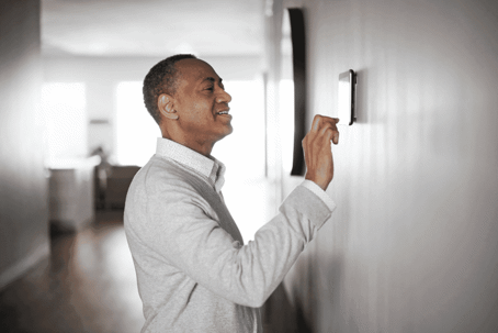 A man checking a thermostat.